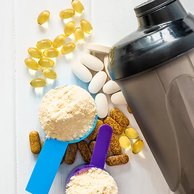 A black blender with a purple and blue measuring cup full of powder.