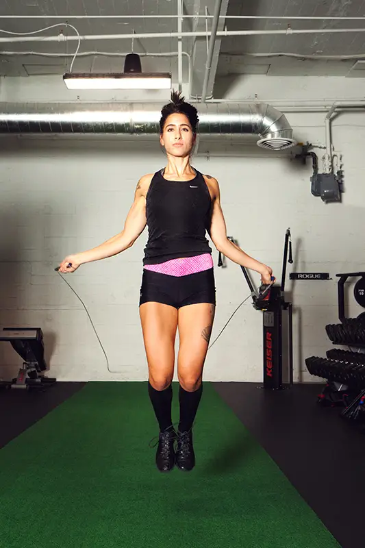 A woman in a black tank top and black shorts is doing a workout.