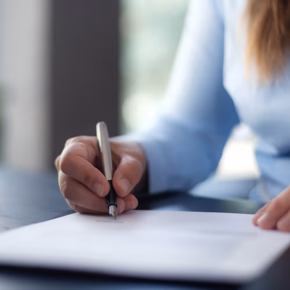 Close-up of a business professional signing a document.