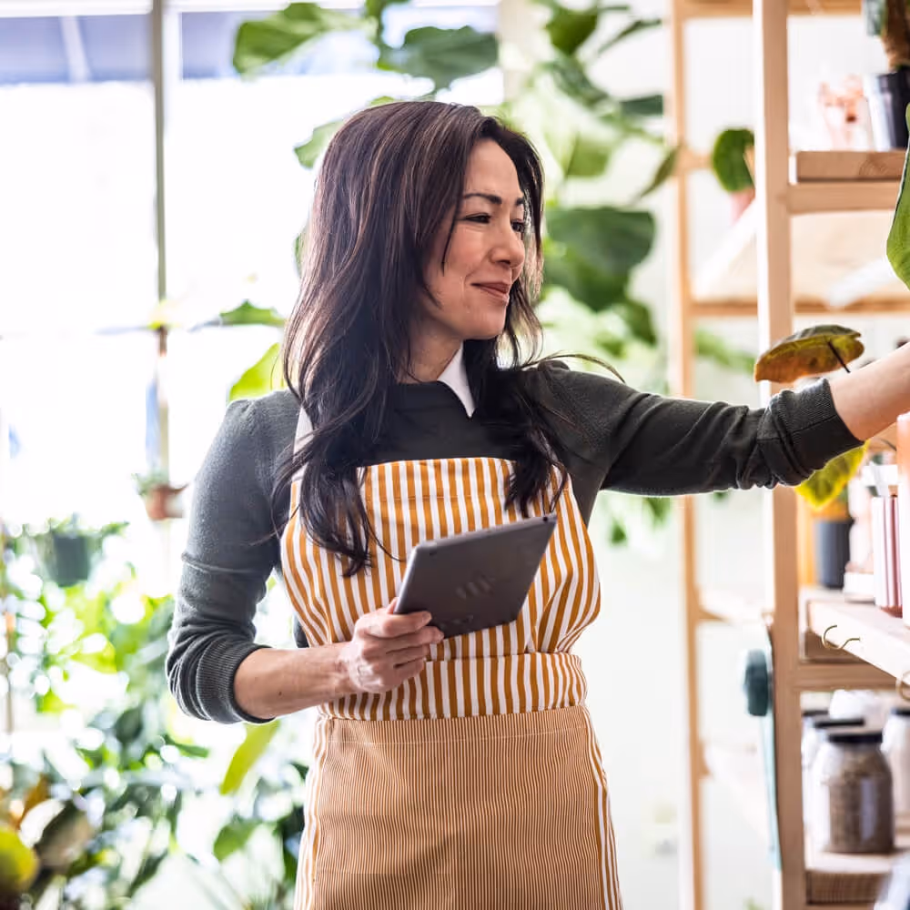 Small business owner using a tablet while managing daily operations in a retail shop.