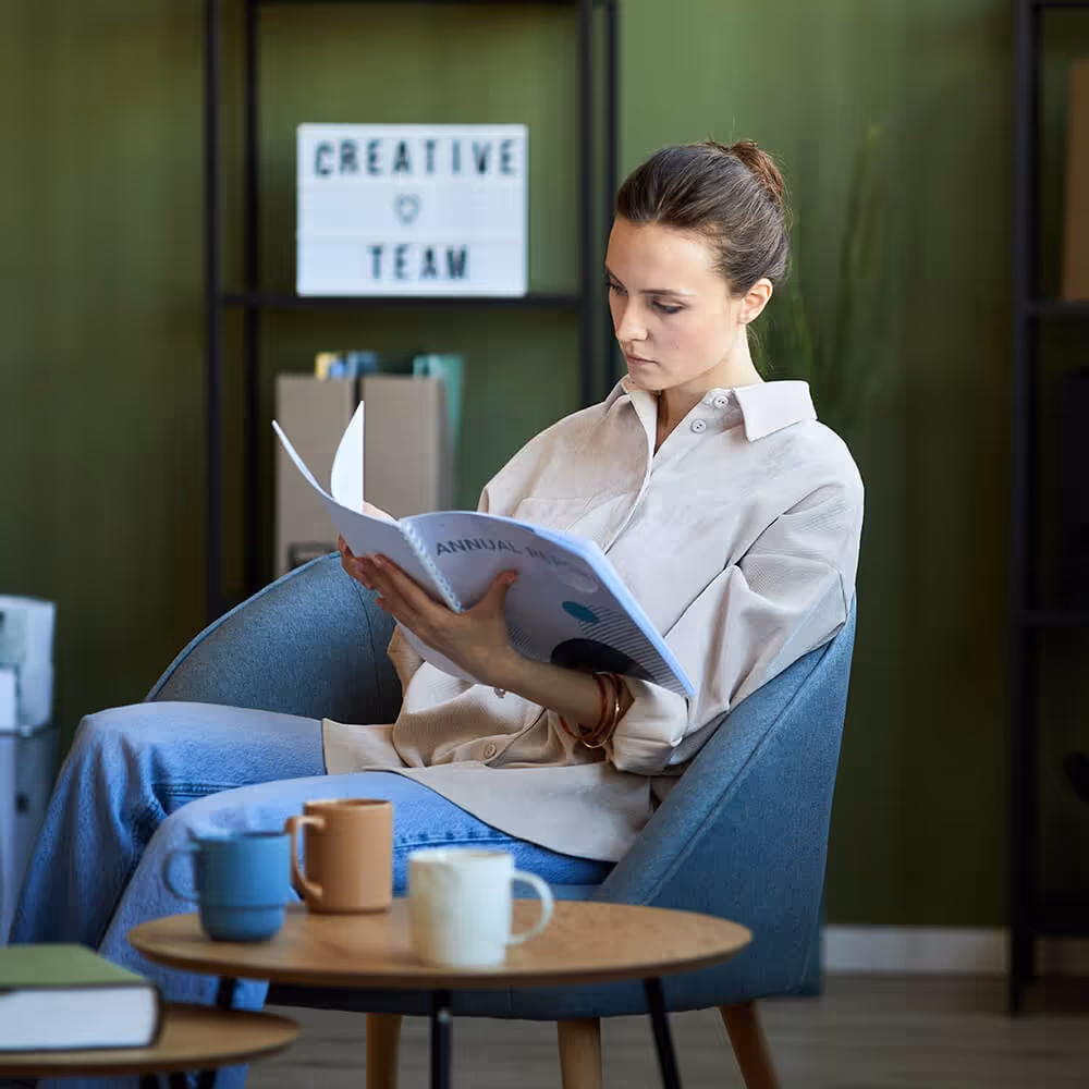 Professional reviewing workplace documents in an office lounge area.