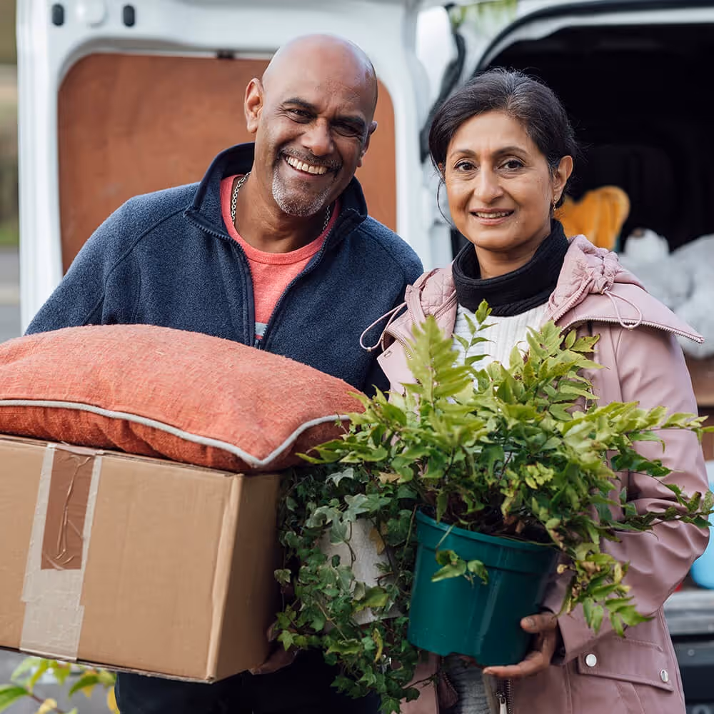 Couple carrying boxes and household items during a move, representing rental property and landlord matters.