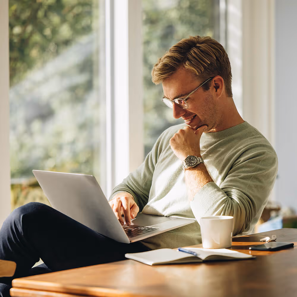 Small business owner using a laptop at home to review information and manage business tasks.