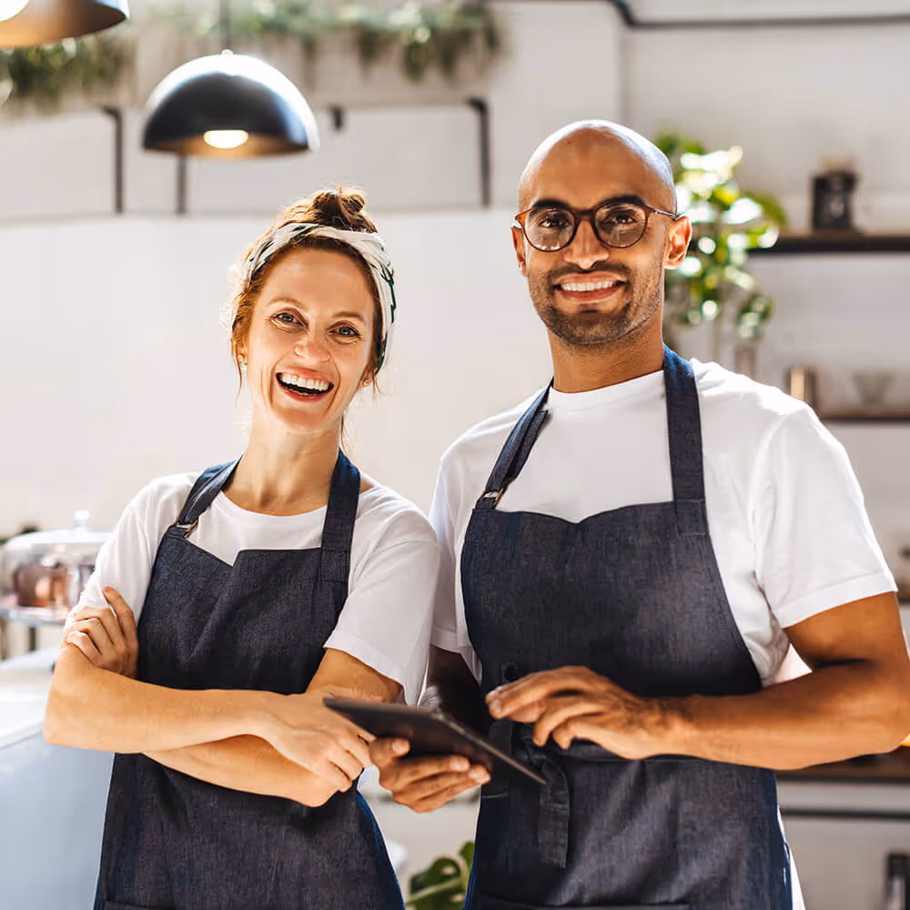 Two small business owners standing in a shop with a tablet, representing daily operations and business support.