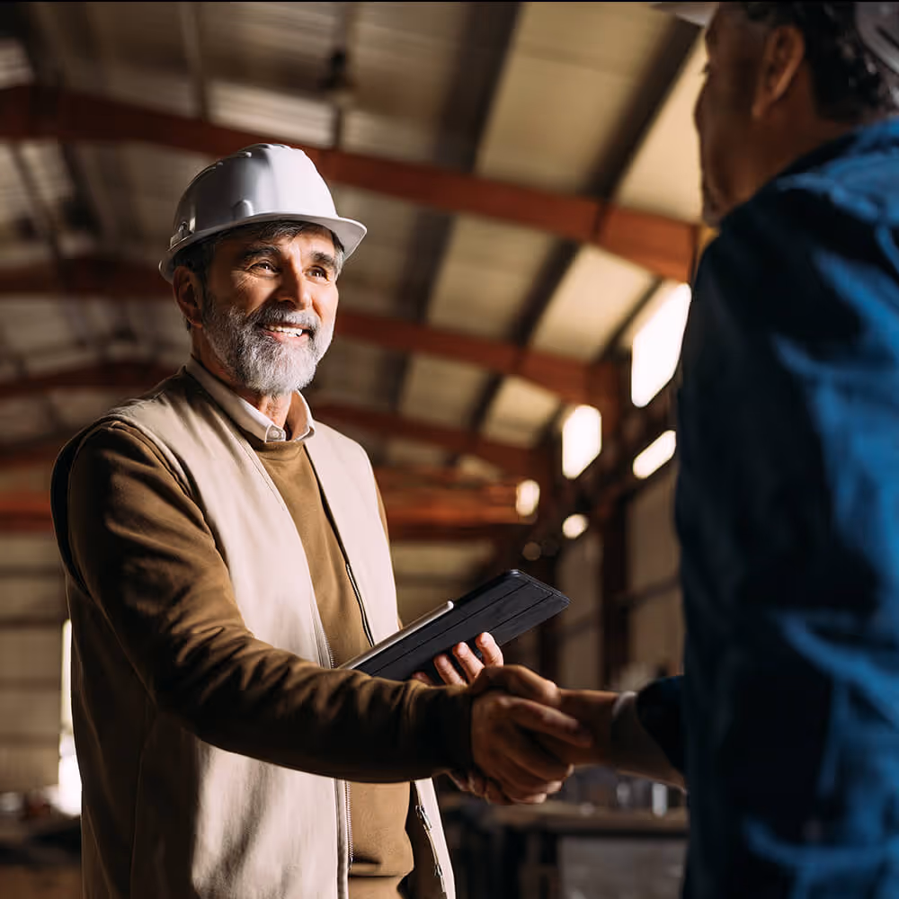 Business professional wearing a hard hat while shaking hands with a client, representing small business add-on legal coverage.
