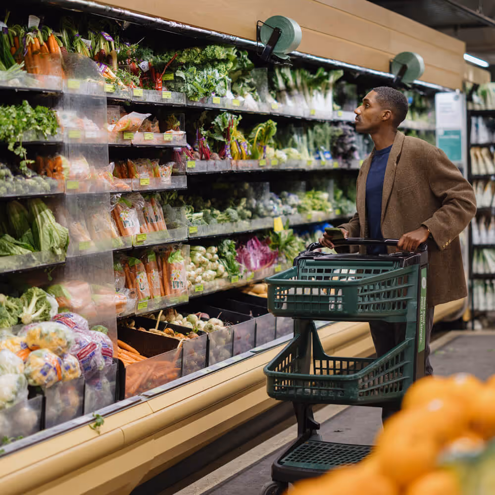 Person grocery shopping in a store, representing everyday consumer purchases and rising household costs.