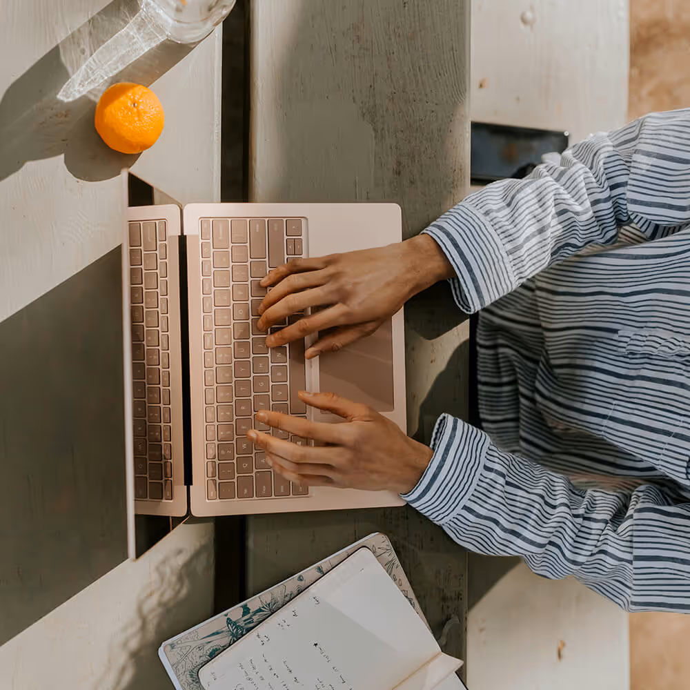 Person using a laptop and notebook at a desk, representing online access to legal support and account tools.