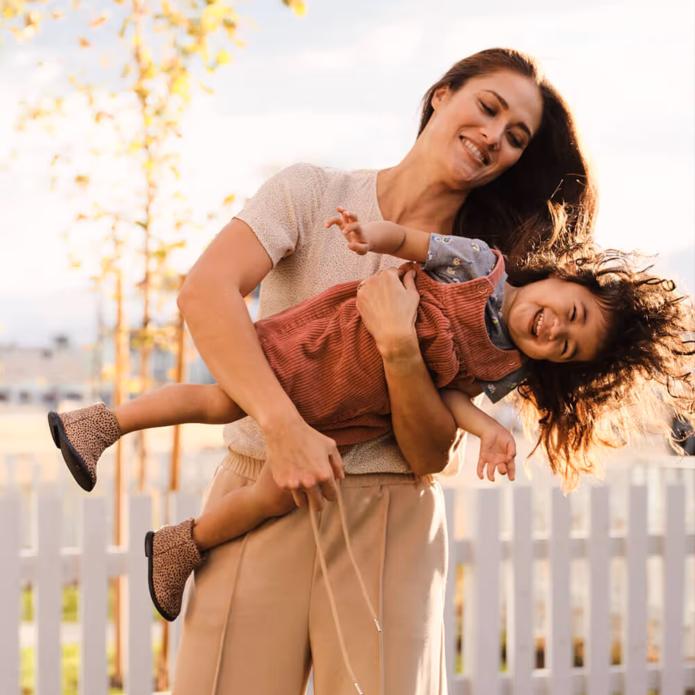 Parent holding a smiling child outdoors, representing family-focused legal support and everyday peace of mind.
