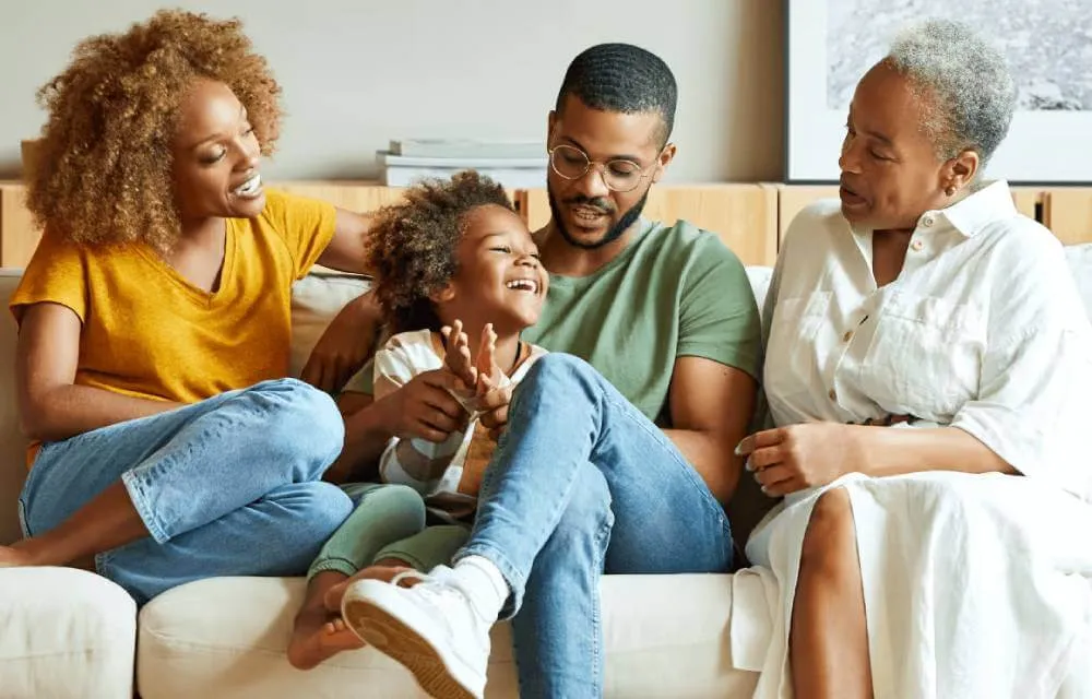 Happy mother, child, father and grandmother sitting on a couch.