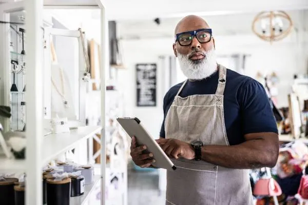 Small business owner looking holding tablet in his store and thinking about selling is business