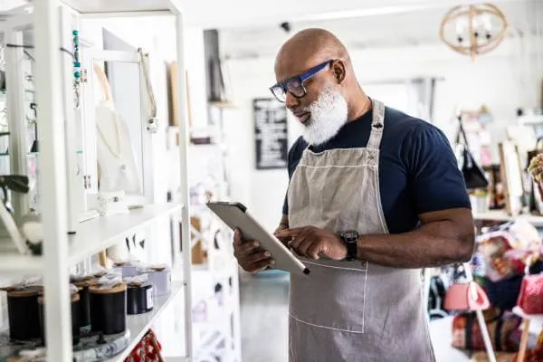 small business owner typing on tablet in his retail shop