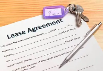 Lease agreement ona table next to apartment keys and ink pen.