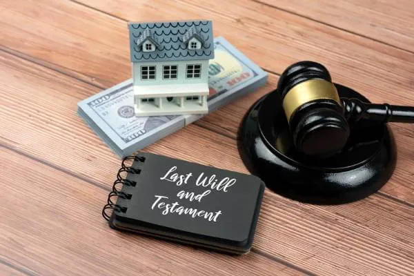 Last Will and Testament next to 100 dollar bills, toy house, and judge's courtroom gavel