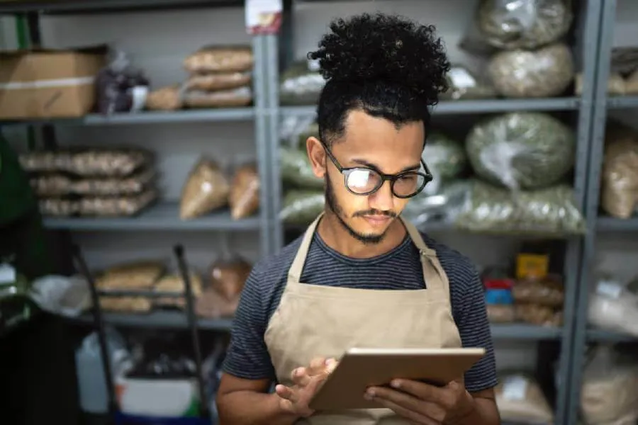 Small business owner using laptop in food storage roomed how to create a DBA for her LLC.