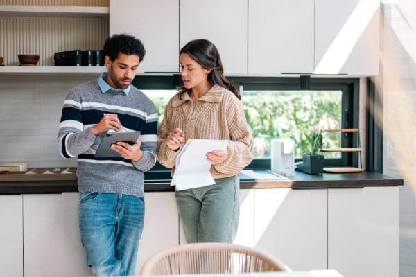 couple in kitchen calculating earnest money for new home purchase
