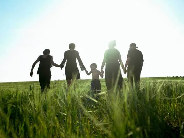 5 family members holding hands as they walk on family property
