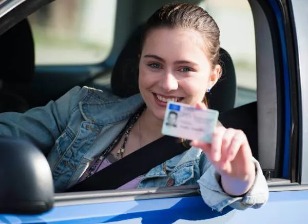 Young woman driver showing her REAL ID state driver's license