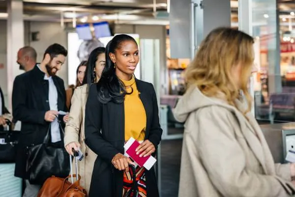 airline passengers holding their travel identification standing in line to board an airplane at an airport