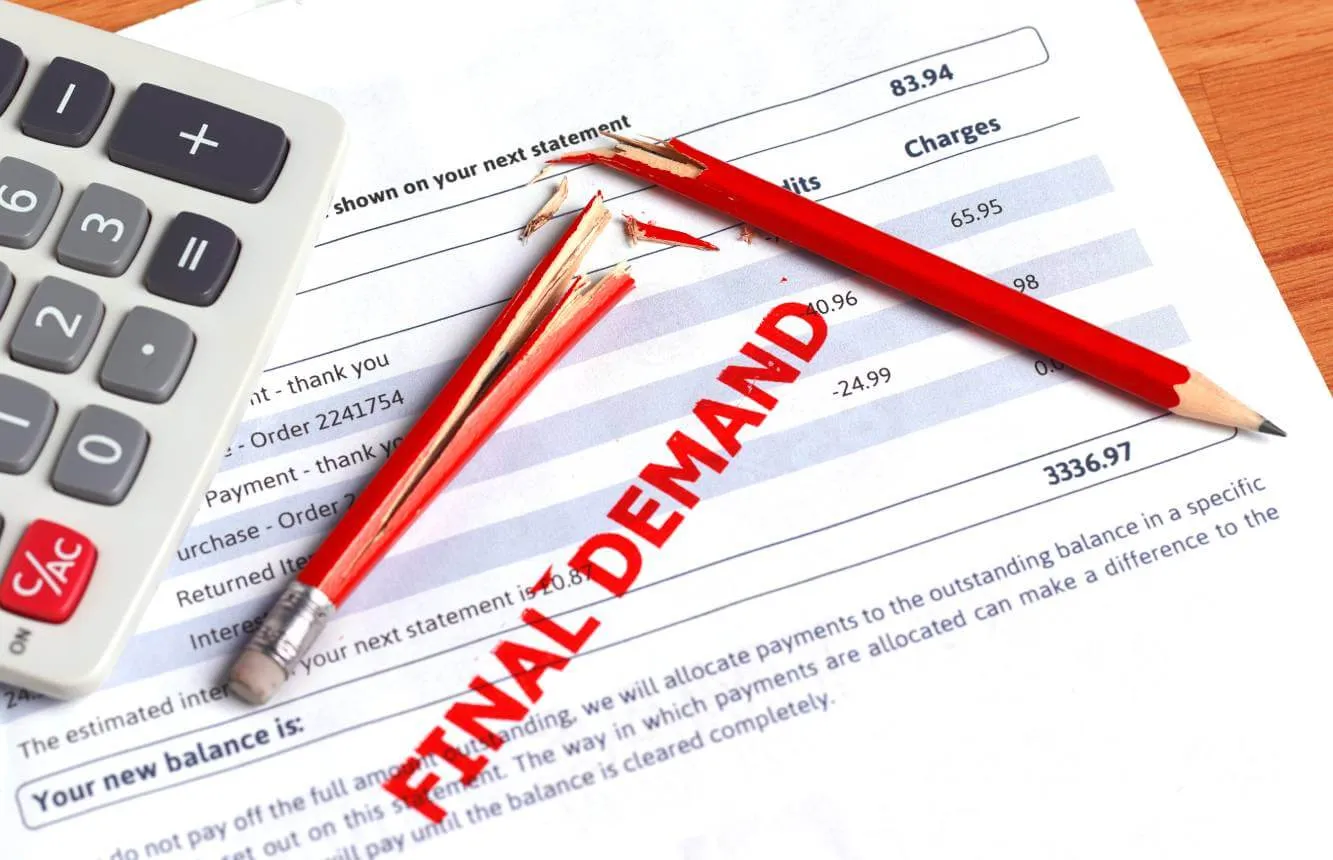 invoice stamped with final demand in read sitting next to a broken red pencil and a calculator