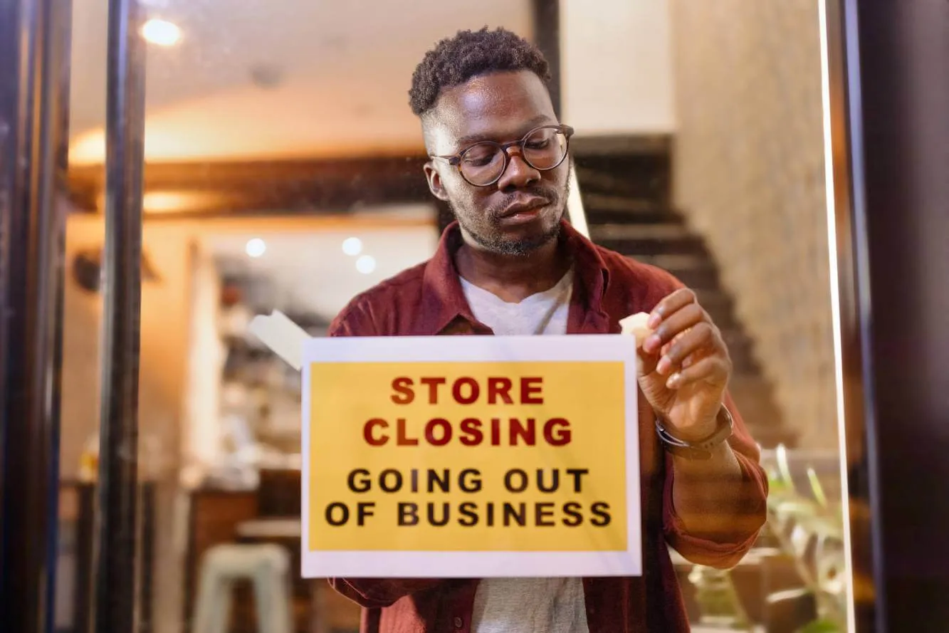 sign being hung on small business door reading: Store Closing. Going Out of Business