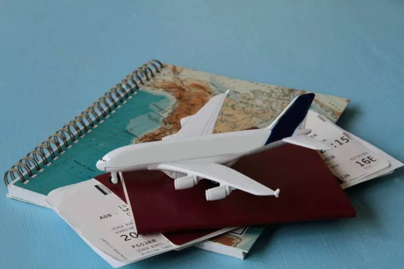 toy airplane, travel identification, passport and map on a table