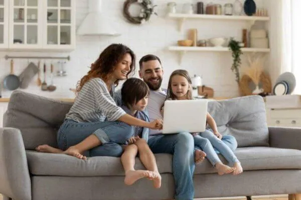 family planning their spring break trip while sitting on living room sofa and viewing a laptop computer