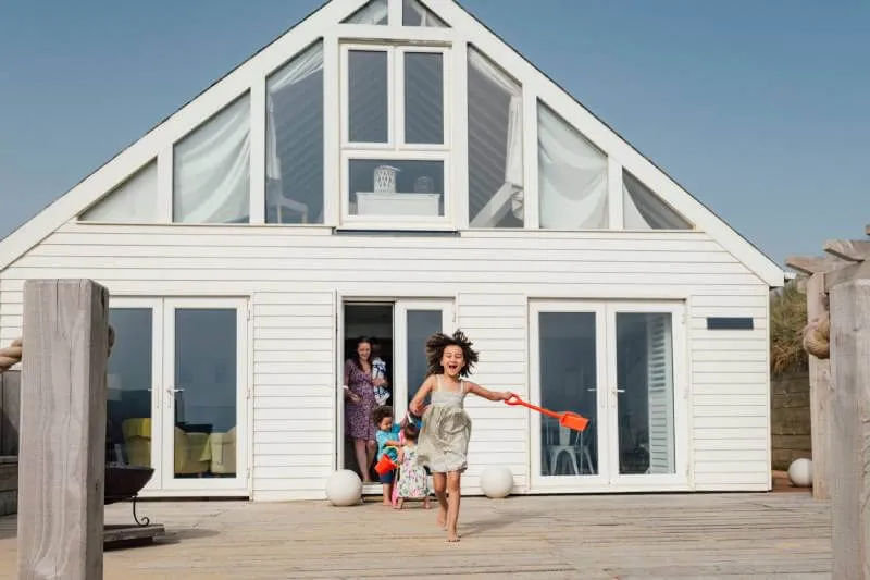Mother and 3 children leaving spring break vacation house to play on the beach.