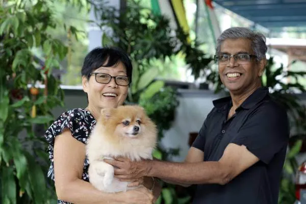 Smiling couple showing off their cute Pomeranian dog