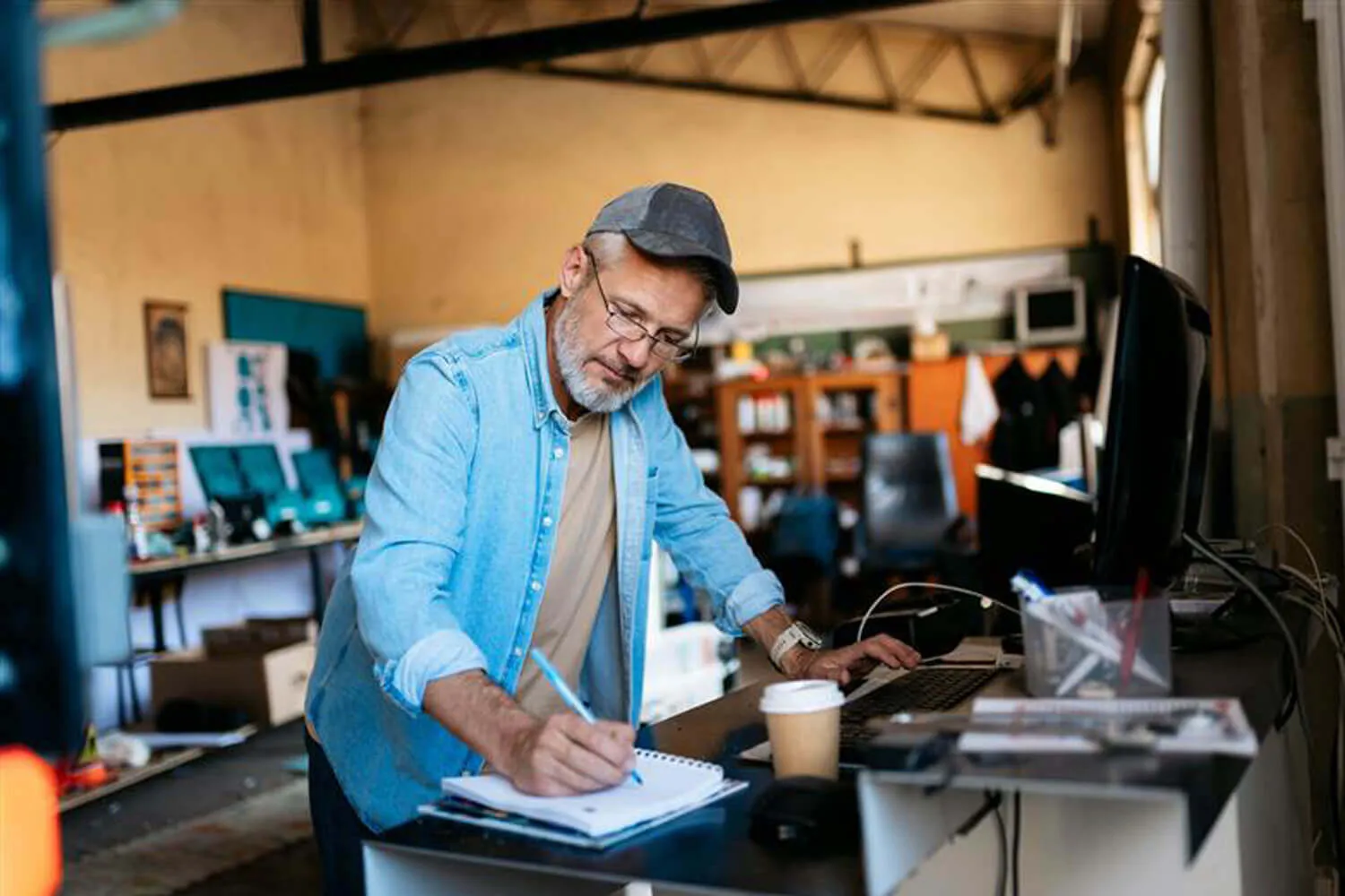Mature entrepreneur writing notes in his workshop