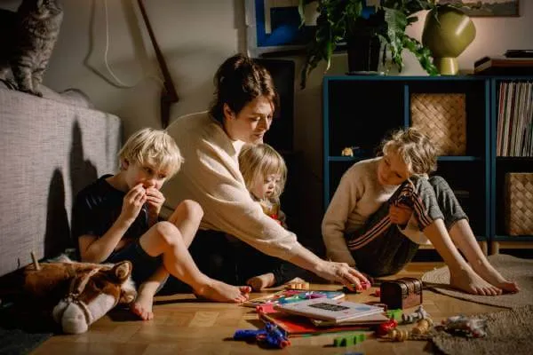 Mother playing with her special needs child and siblings on the floor in the living room