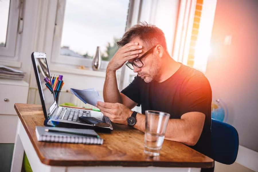 Stressed man reviewing financial documents at home