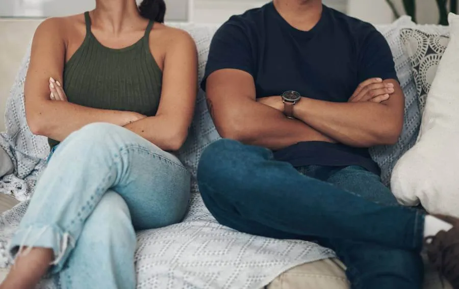 Divorcing couple next to each other with arms crossed on couch