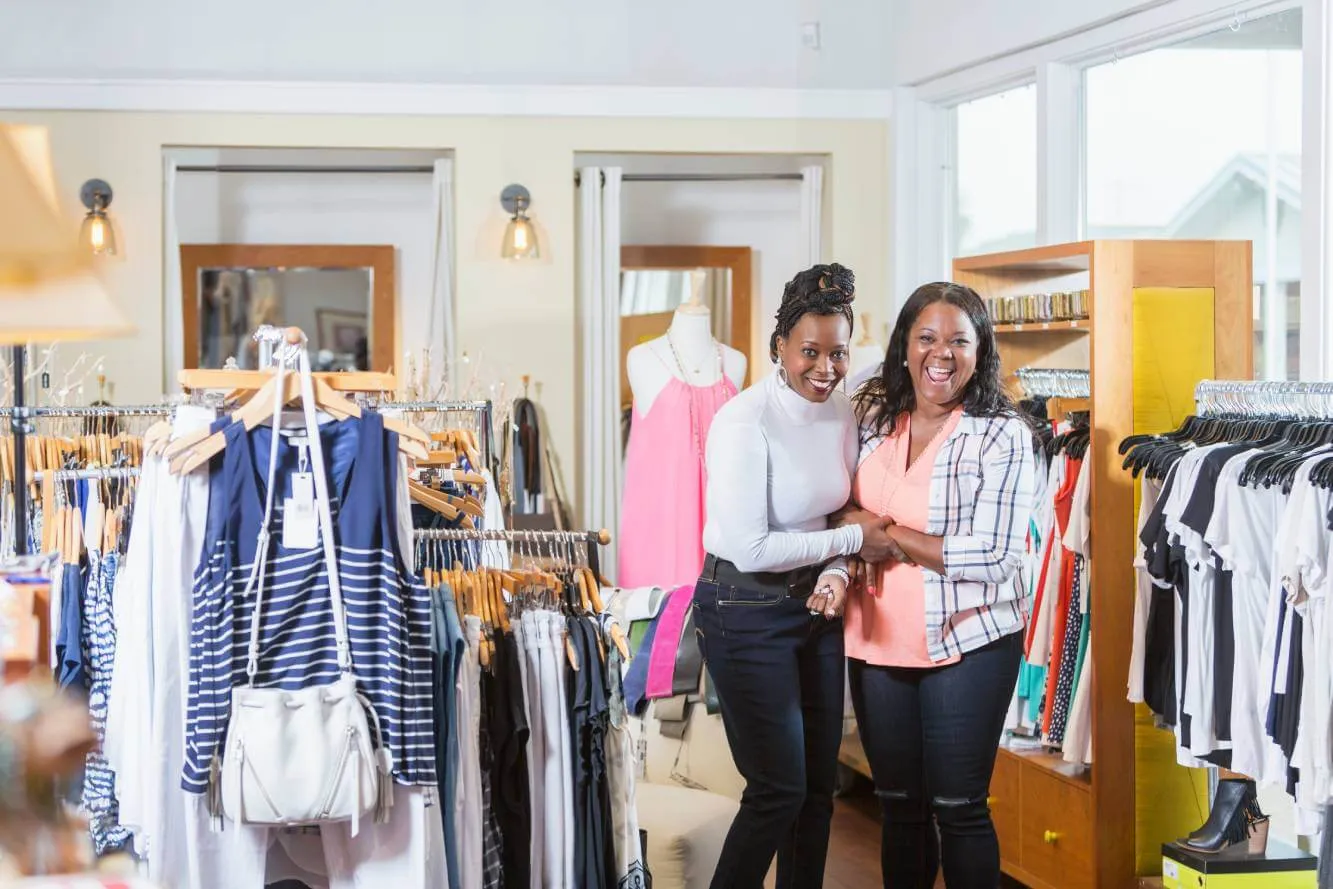 smiling small business women's clothing store owners in their shop