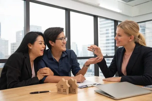 lawyer handing the keys to a man for his new home purchase as his wife looks on