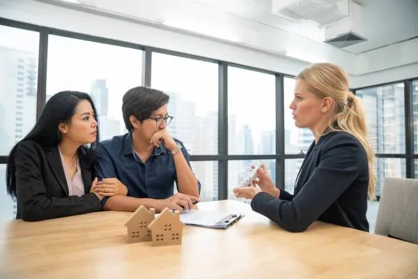 lawyer advising couple on a home purchase agreement while showing them a calculator