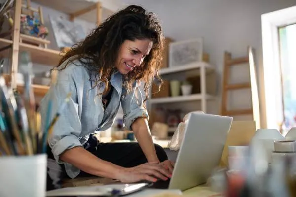 Smiling business owner typing on her laptop in her workplace