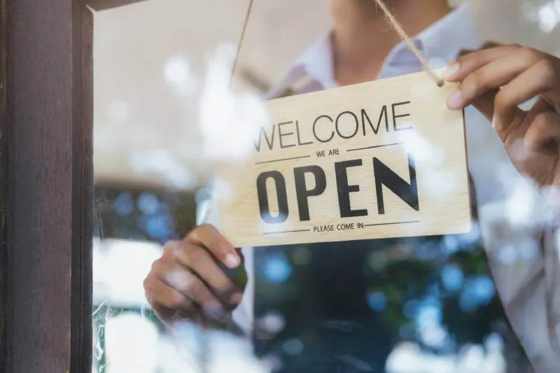 Business owner hanging a welcome we are open please come in sign on business door