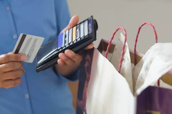 man placing a credit card in his wallet after making a purchase at a store