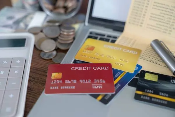 4 credit cards sitting on a laptop next to calculator, coins, tracking document and ink pen