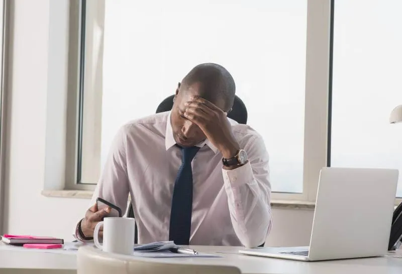 Employee displaying stress while reviewing legal documents at their desk, illustrating workplace disruption from legal challenges
