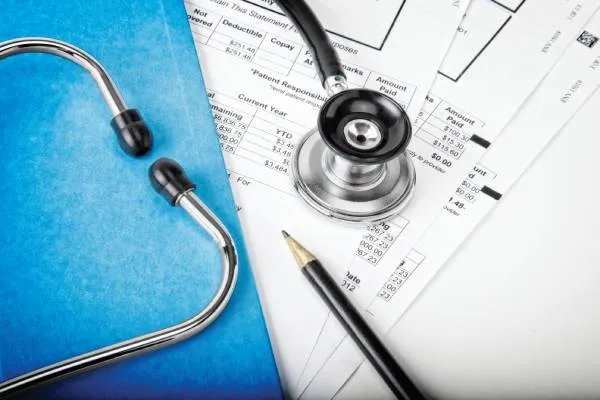 medical bills, blue folder, stethoscope and pencil