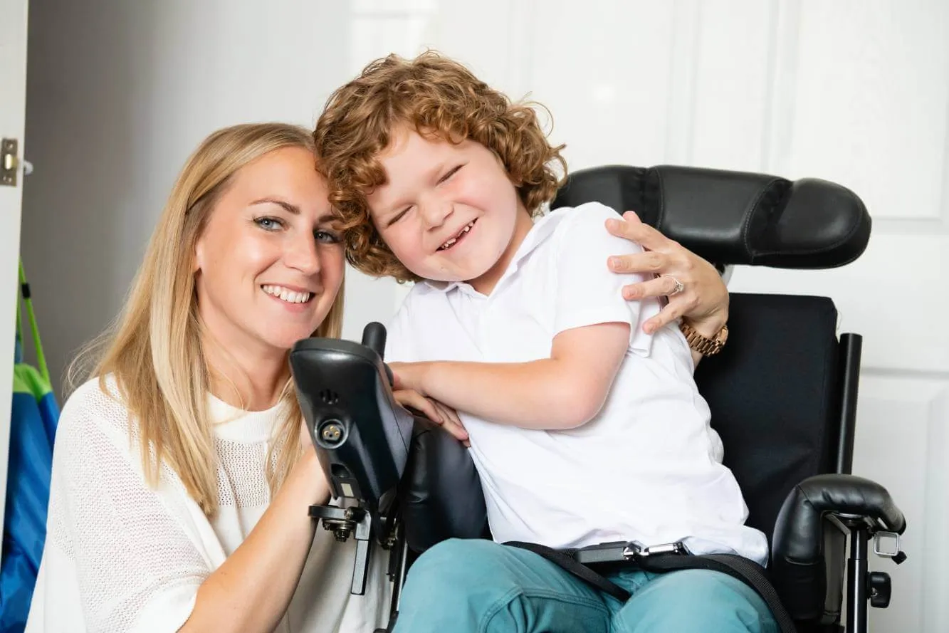 Young boy in a wheelchair sitting next to his mother