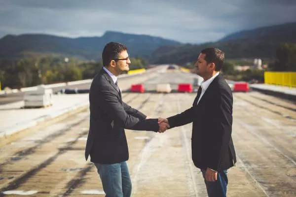 businessmen shaking hands on highway under construction after eminent domain