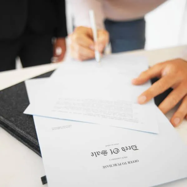 woman signing an offer to purchase a house deed of sale