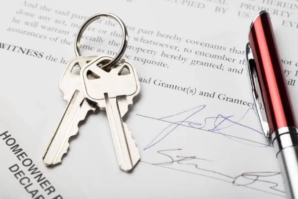 signed home purchase agreement with a set of keys and ink pen