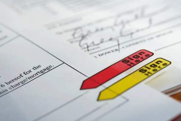 sign here red and yellow stickers on a home purchase agreement