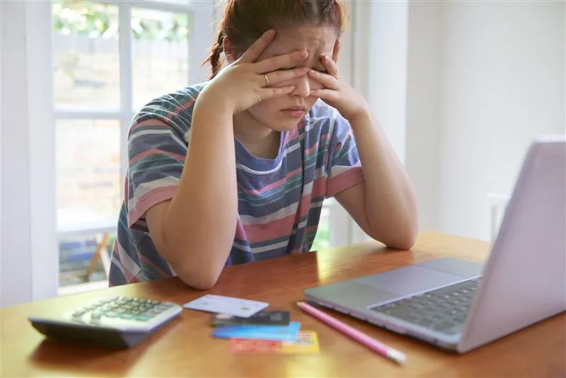 Woman at her computer looking overwhelmed and stressed juggling multiple loans and payments