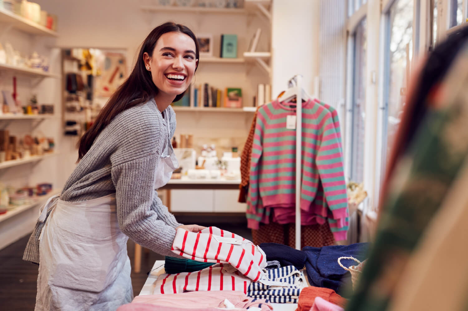 A woman setting out clothes for sale at her business