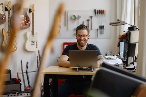 A small business owner on his laptop in a guitar shop, setting up an EIN for his LLC.