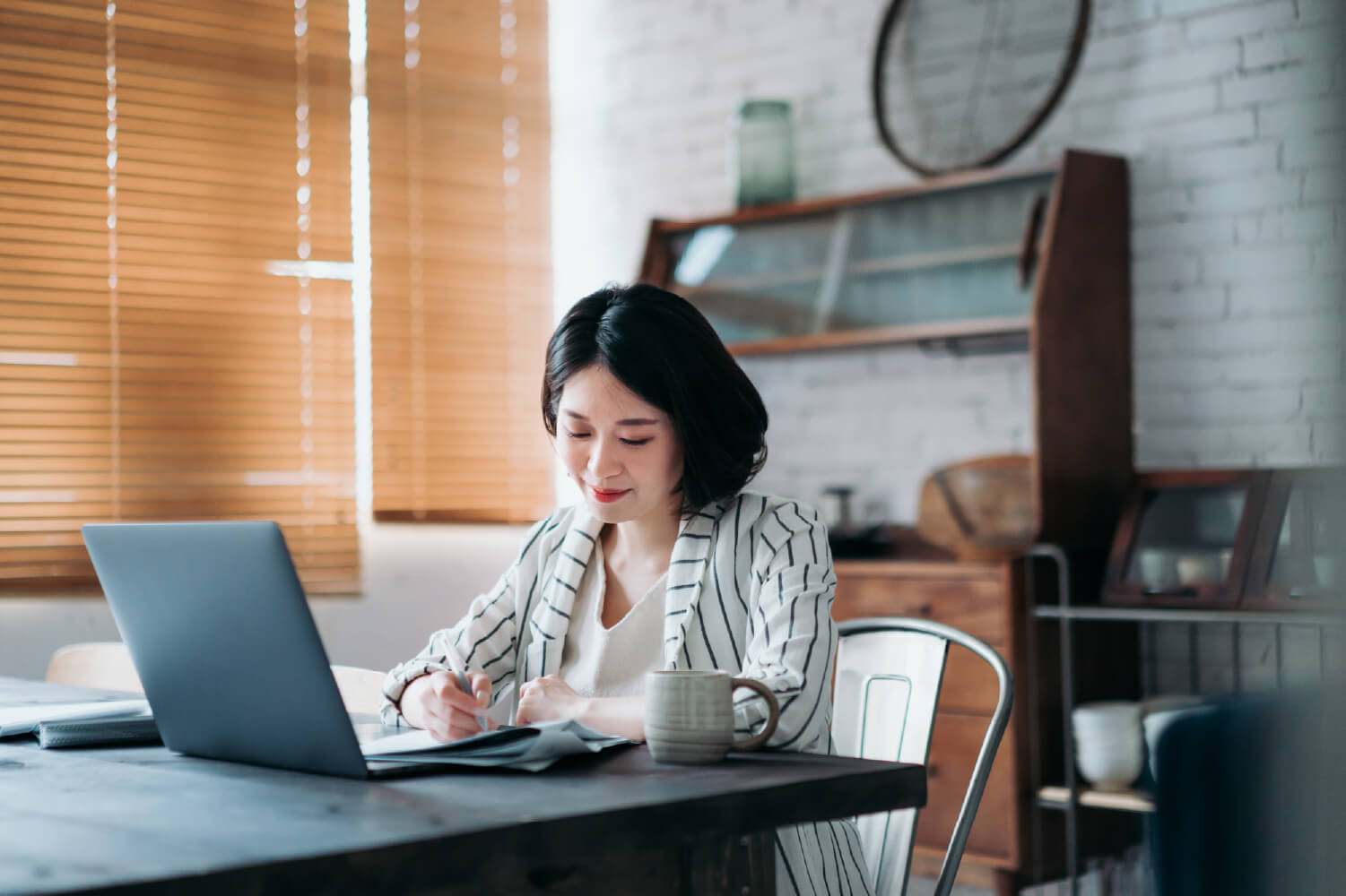 A woman signing a document at a laptop.
